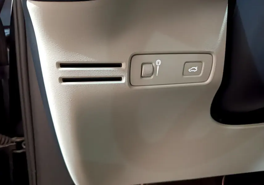 Gros plan sur le panneau latéral beige avec commande d'éclairage et ouverture de coffre du Volvo XC40 noir 2020.