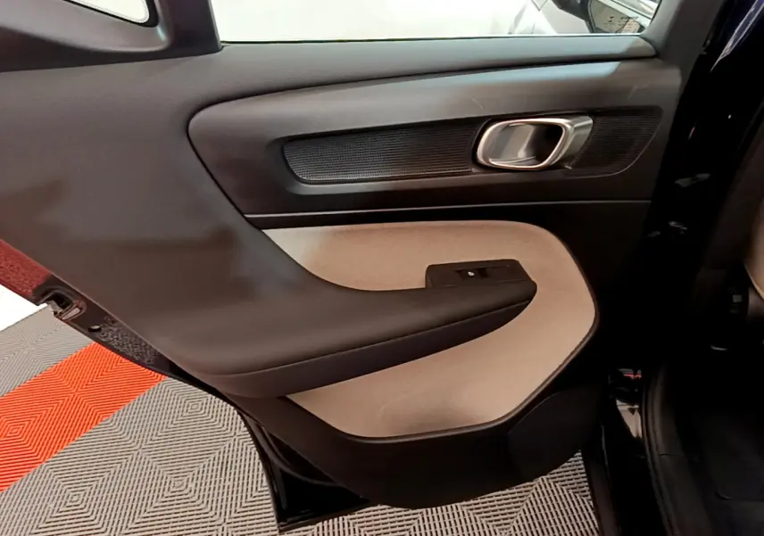 Porte arrière gauche intérieure du Volvo XC40 T3 2020, avec panneau bicolore noir et beige et poignée argentée.