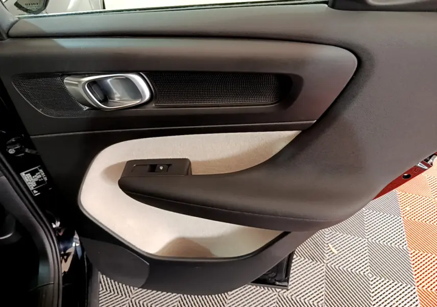Gros plan sur la porte arrière gauche intérieure du Volvo XC40 noir, avec panneau bicolore beige et noir.