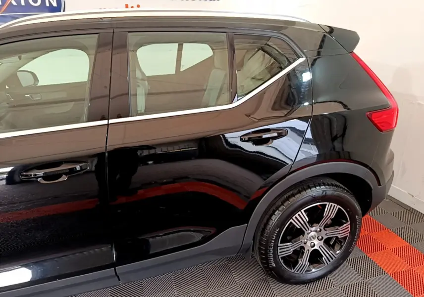 Vue côté droit arrière du Volvo XC40 T3 noir, soulignant la ligne de toit chromée et la jante alliage distinctive.