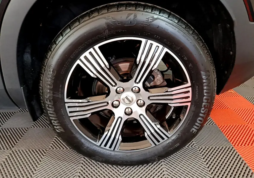 Gros plan sur la roue avant droite du Volvo XC40 noir, avec jante alliage bicolore et pneu Bridgestone.