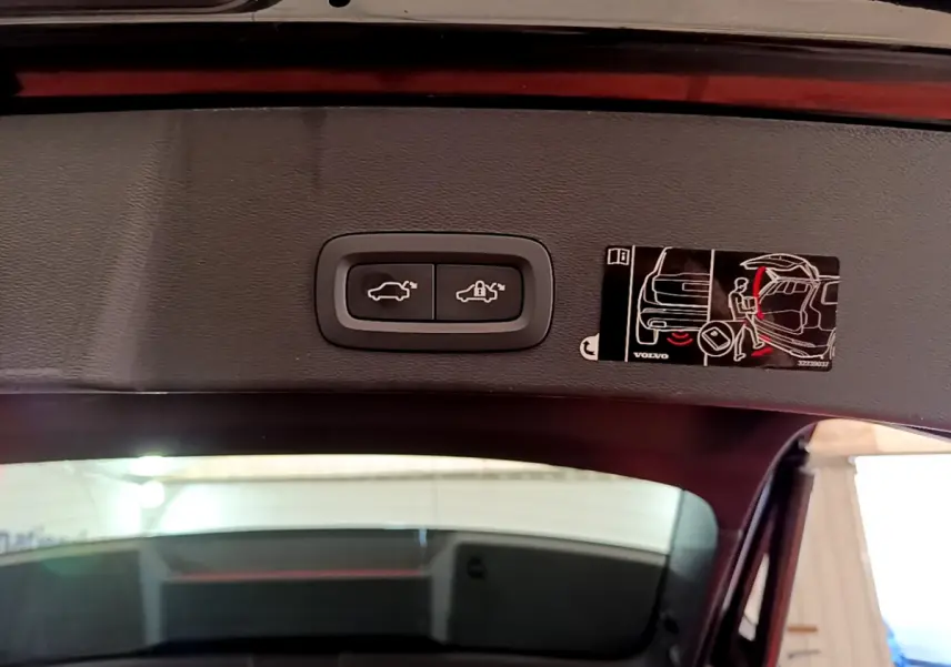 Gros plan sur les boutons d'ouverture et de verrouillage du coffre électrique du Volvo XC40 noir, vue depuis l'intérieur du coffre.