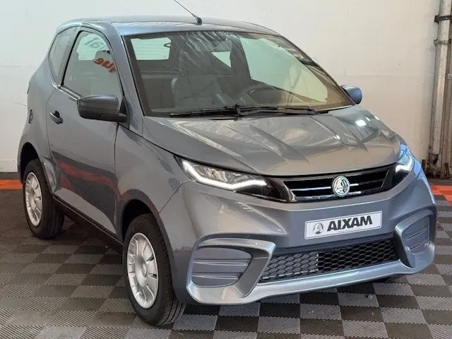 Vue 3/4 avant d'une Aixam Ambition 0.5 City Pack gris foncé avec rétroviseur caméra côté gauche.
