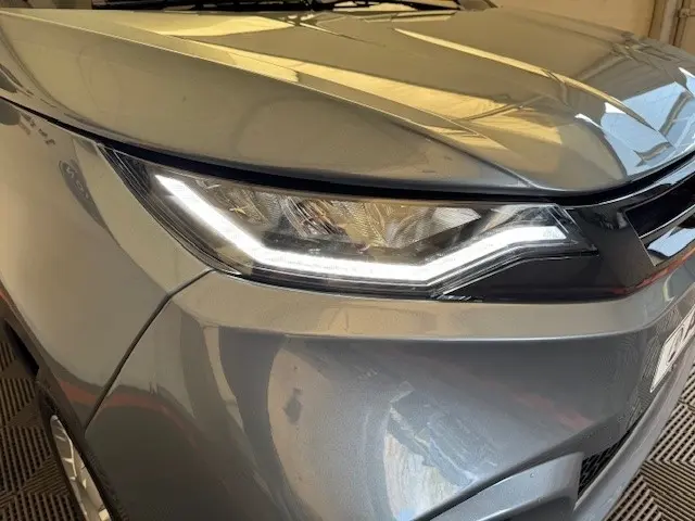 Gros plan sur le phare avant gauche d’une Aixam Ambition 0.5 City Pack gris foncé, avec ligne LED distinctive.