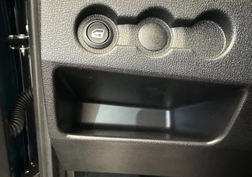 Détail intérieur montrant le bouton d'ouverture du coffre sur la porte côté conducteur d'une Aixam Ambition gris foncé.