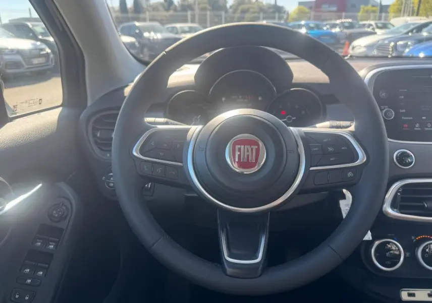 Vue centrée sur le volant du Fiat 500X 2024, avec tableau de bord et commandes visibles en intérieur.