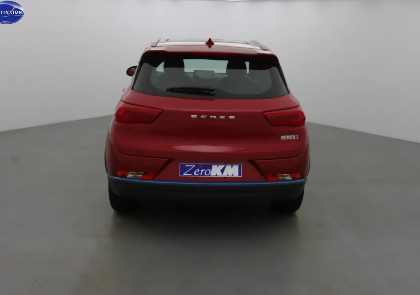 Vue arrière d'un SUV électrique SERES 3 rouge solaire métal avec logo et plaque Zero KM visible.
