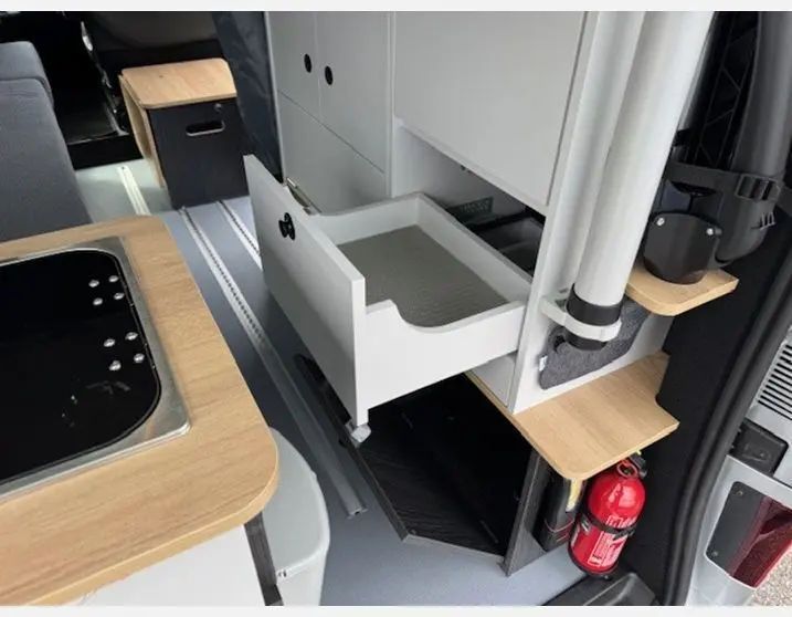 Intérieur du Renault Trafic Fourgon gris Highland, vue sur tiroir ouvert et aménagement cuisine bois clair.