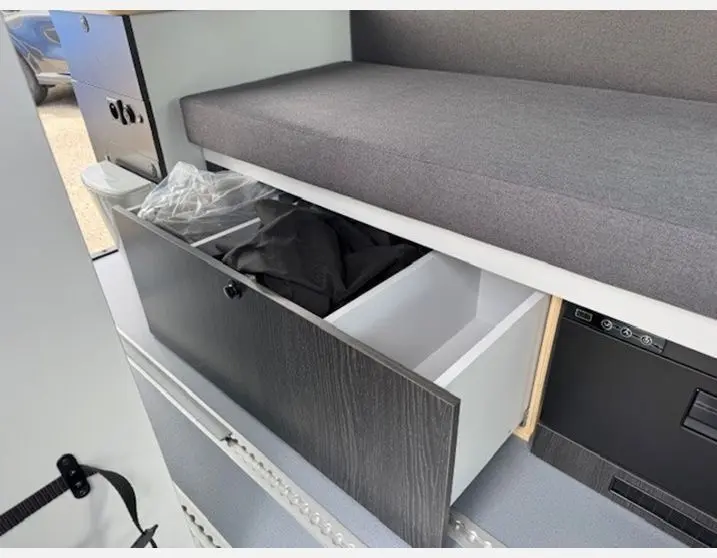 Rangement ouvert sous banquette grise dans l'aménagement intérieur du Renault Trafic Fourgon gris Highland.