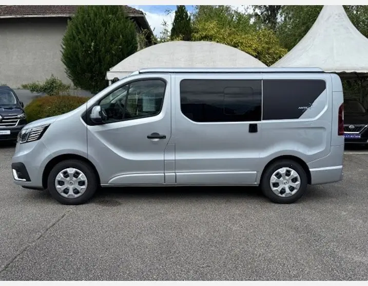 Profil côté gauche du Renault Trafic Fourgon gris Highland avec vitres latérales surteintées et enjoliveurs 16 pouces.