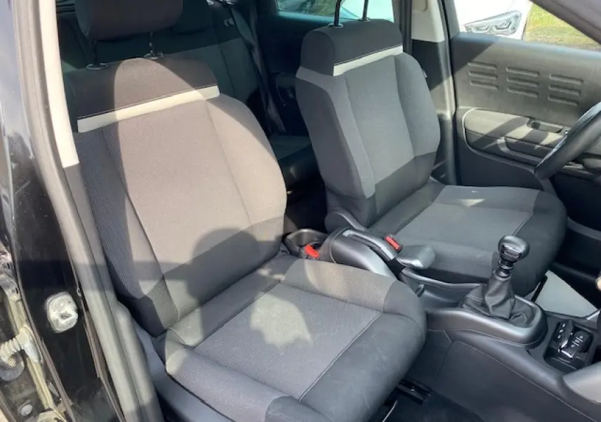 Intérieur avant du Citroën C3 Aircross noir 2019, vue côté gauche sur sièges tissu gris et levier de vitesse manuel.