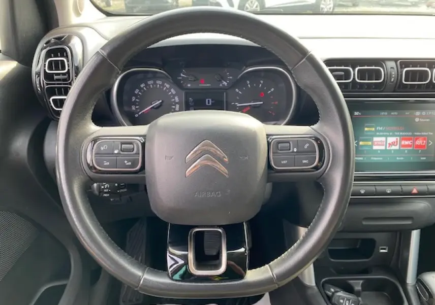 Vue intérieure centrée sur le volant en croûte de cuir du Citroën C3 Aircross noir avec tableau de bord et écran tactile.