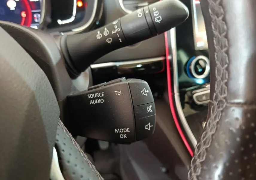 Gros plan sur la commande audio et téléphone au volant cuir perforé du Renault Espace noir, tableau de bord et écran tactile en arrière-plan.