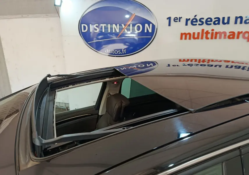 Toit ouvrant ouvert vu de dessus sur un Renault Espace noir, intérieur cuir visible, en stationnement intérieur.