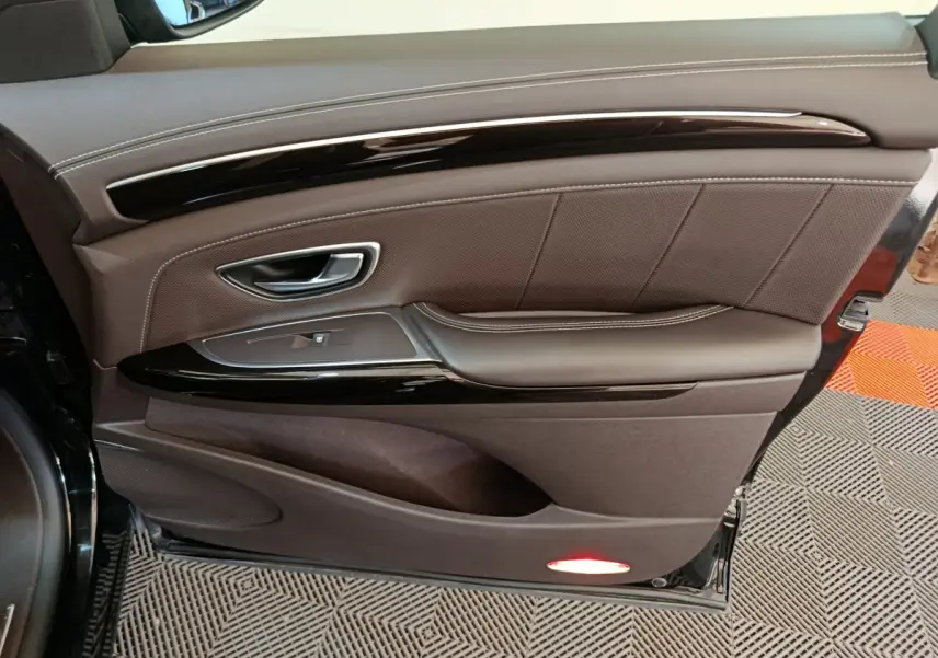 Vue rapprochée de la porte côté gauche noire du Renault Espace Initiale Paris, avec garniture cuir marron et insert laqué noir.