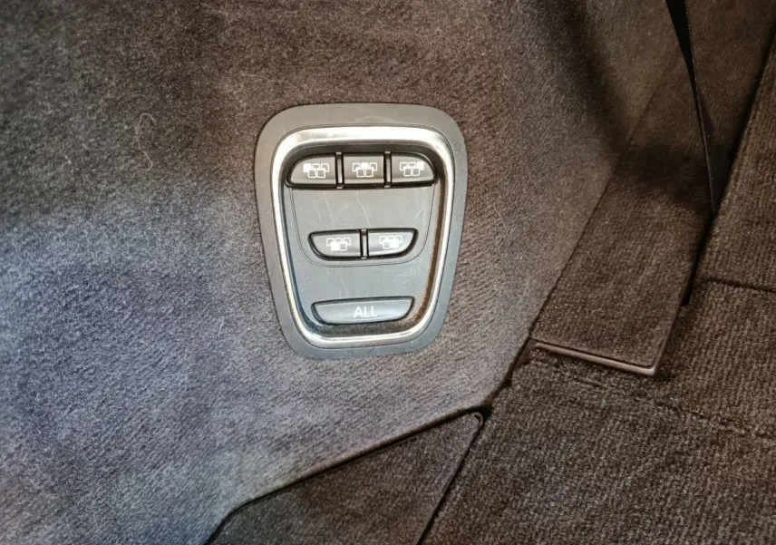 Boutons de commande des sièges rabattables dans le coffre du Renault Espace noir, vue en gros plan.