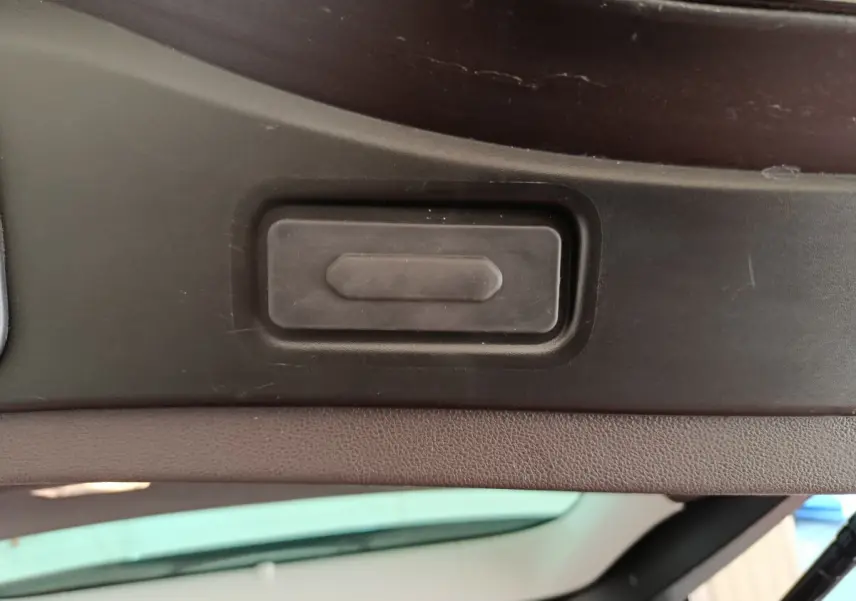 Gros plan sur le bouton d'ouverture électrique du coffre du Renault Espace Initiale Paris noir, vue intérieure du hayon ouvert.