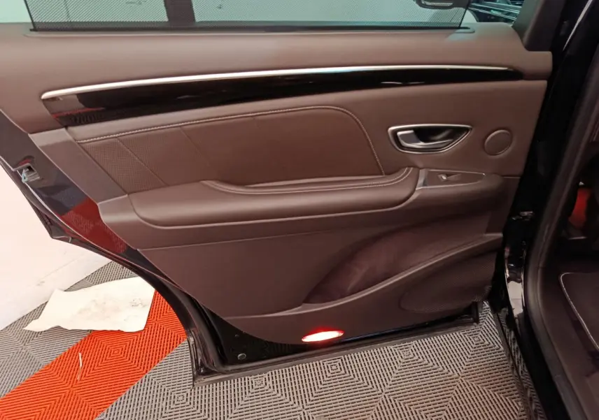 Gros plan sur la porte arrière gauche intérieure en cuir marron du Renault Espace noir 2018, avec éclairage de sécurité rouge.
