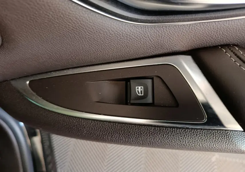 Bouton de commande de lève-vitre sur la porte côté gauche d'un Renault Espace noir 2018 Initiale Paris.