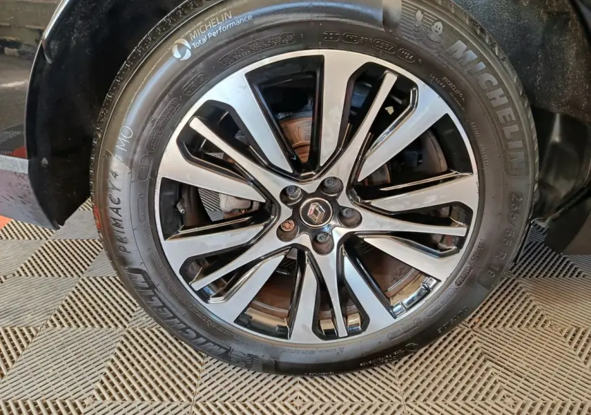 Gros plan sur la jante alliage noire et argentée avec logo Renault au centre, montée sur pneu Michelin d'un Renault Espace noir.