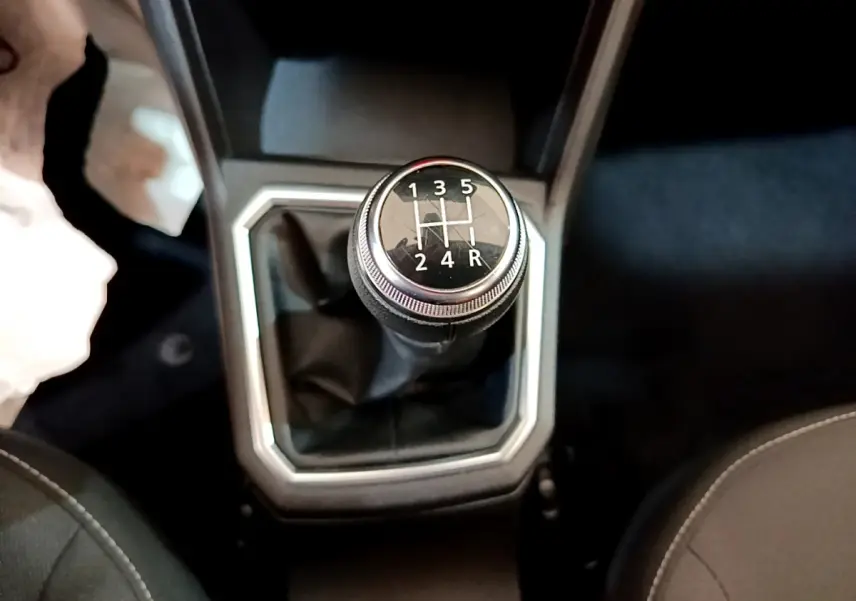 Le levier de vitesses manuel noir de la Dacia Sandero Confort TCe 90 vue de dessus, entouré de garniture grise.