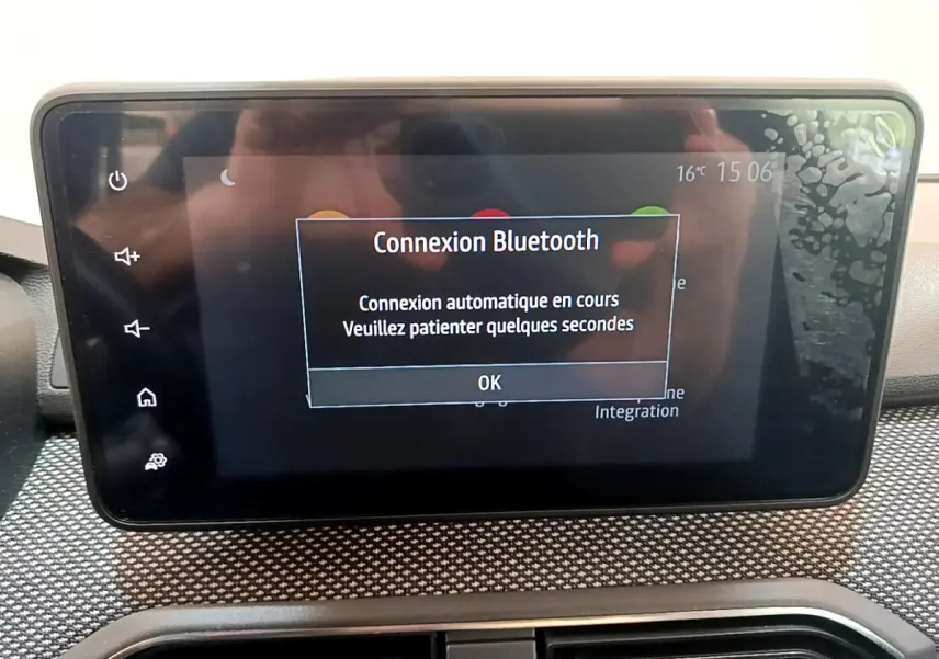 Écran tactile central affichant une connexion Bluetooth en cours dans le tableau de bord d'une Dacia Sandero blanche.