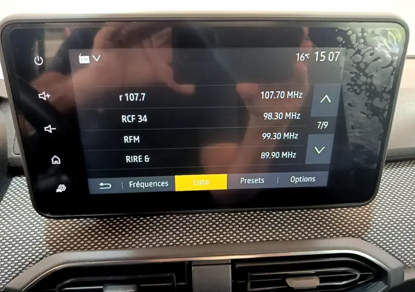 Écran tactile central affichant les stations radio dans l'habitacle d'une Dacia Sandero Confort blanche.