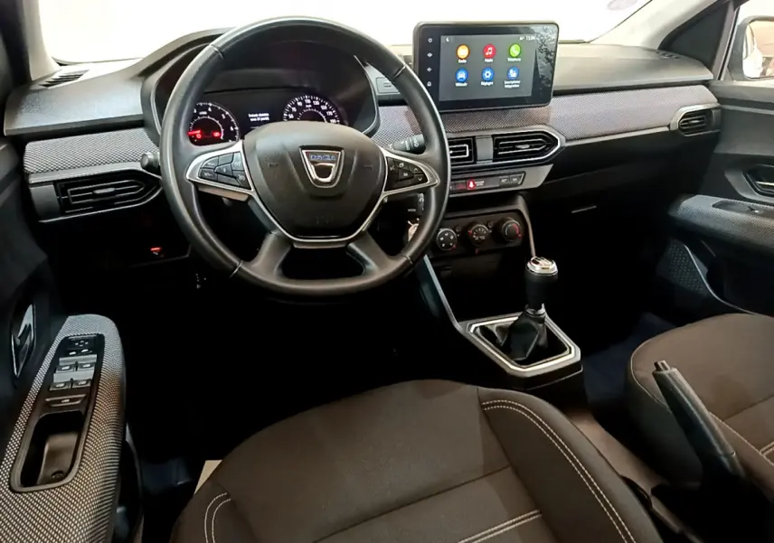 Intérieur de la Dacia Sandero Confort 2022, vue avant centrée sur le volant cuir et l'écran tactile multifonctions.