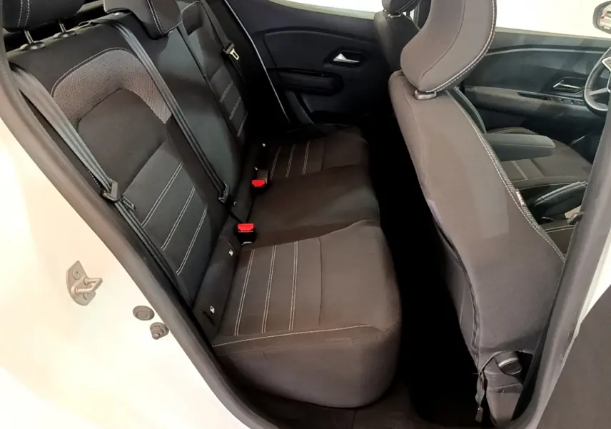 Vue intérieure côté gauche montrant la banquette arrière noire et les sièges avant d'une Dacia Sandero blanche 2022.