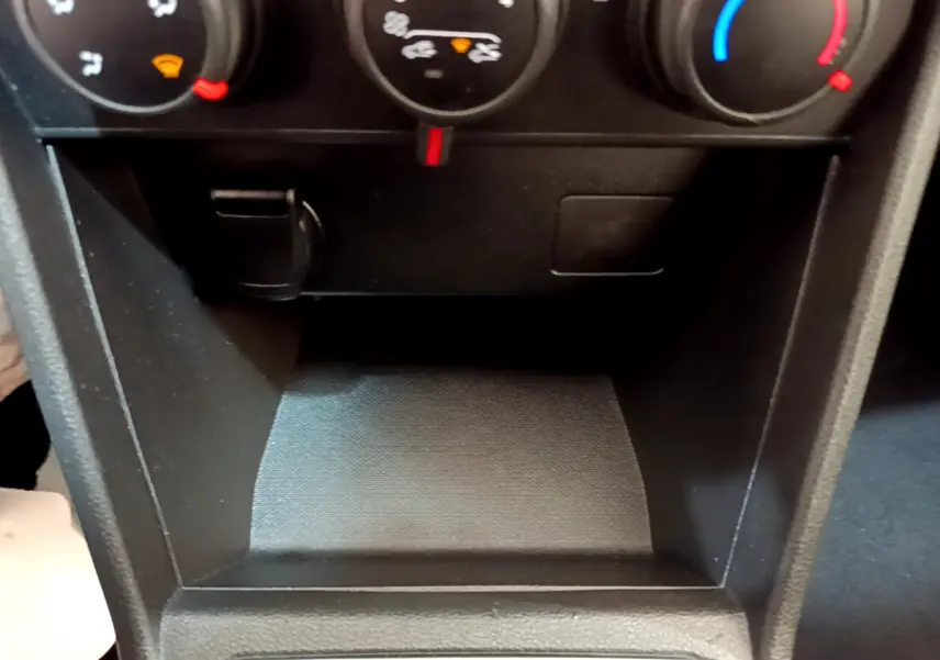 Gros plan sur la console centrale noire de la Dacia Sandero Confort TCe 90, montrant les commandes de climatisation.
