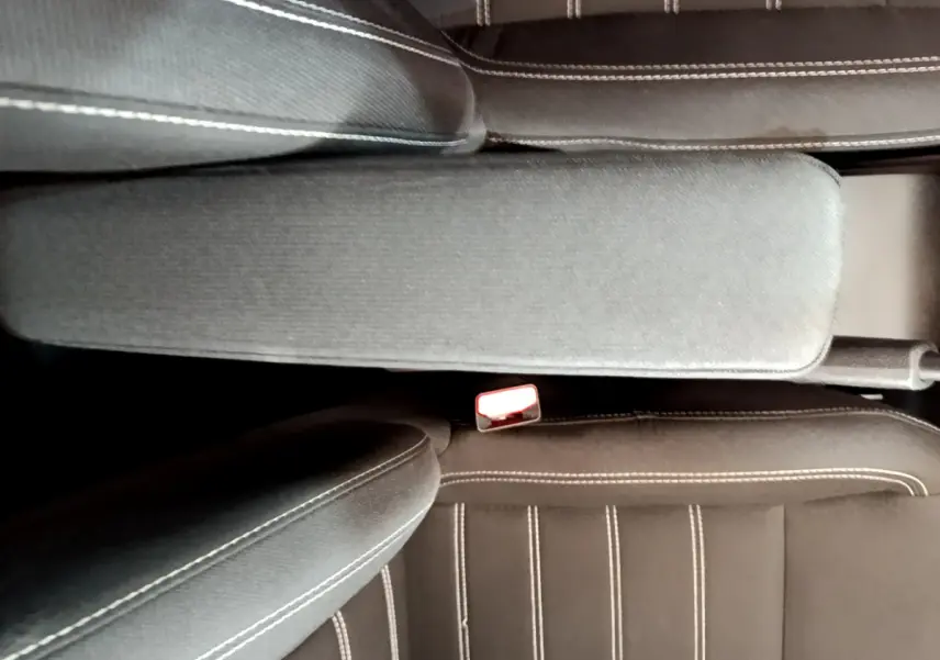 Vue rapprochée de l'accoudoir central et des sièges noirs avec surpiqûres blanches de la Dacia Sandero Confort 2022.