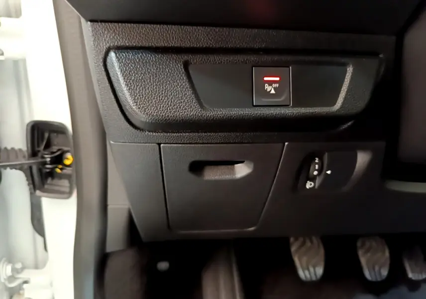 Vue rapprochée du tableau de bord côté gauche d'une Dacia Sandero blanc 2022, avec bouton désactivation capteurs de stationnement.
