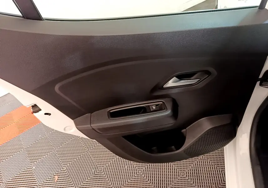 Vue rapprochée de la porte arrière droite blanche d'une Dacia Sandero 2022 avec poignée intérieure et commande de vitre électrique.