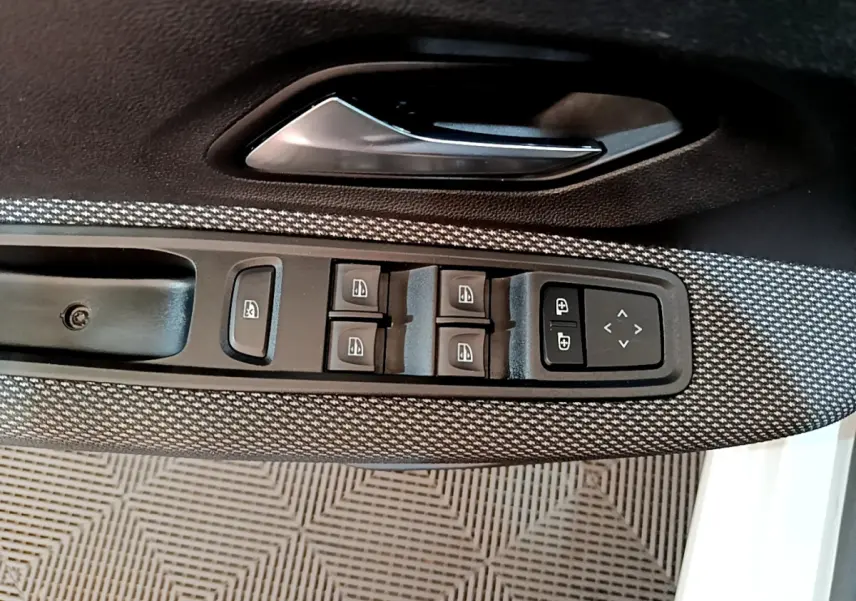Détail des commandes des vitres et rétroviseurs sur la porte côté conducteur d'une Dacia Sandero blanche 2022 Confort TCe 90.