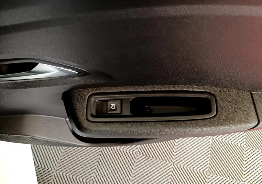 Gros plan sur la commande de lève-vitre côté conducteur de la Dacia Sandero Confort blanche de 2022.