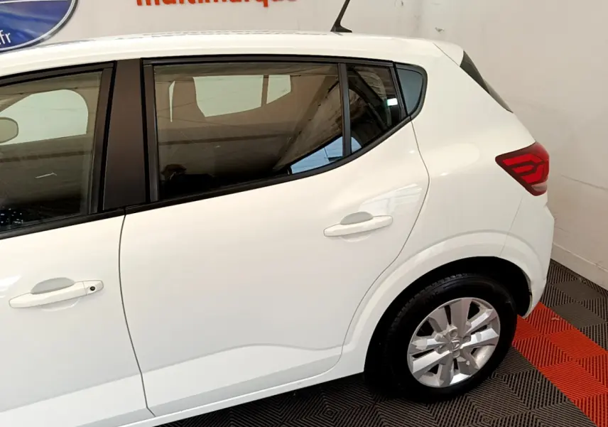 Vue latérale côté droit d'une Dacia Sandero blanche 2022, mettant en valeur les lignes épurées et les feux arrière LED.