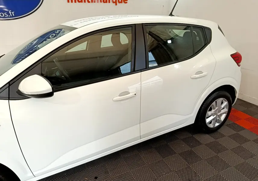 Profil côté gauche de la Dacia Sandero Confort blanche 2022, montrant ses lignes épurées et ses jantes alliage.