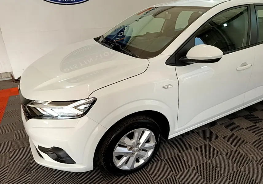 Vue 3/4 avant droit d'une Dacia Sandero Confort TCe 90 blanche avec phares LED et jantes alliage visibles.