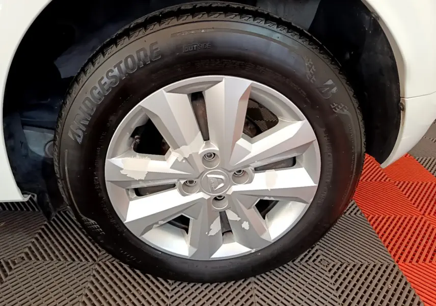 Gros plan sur la roue avant droite de la Dacia Sandero blanche, mettant en valeur la jante argentée et le pneu Bridgestone.