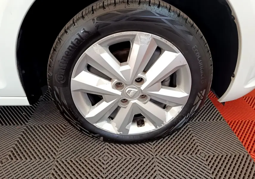 Gros plan sur la roue avant gauche blanche d'une Dacia Sandero Confort TCe 90 avec jante alliage et pneu Continental.