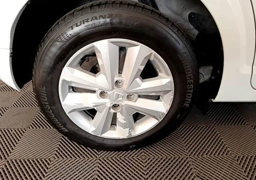 Gros plan sur la roue avant droite blanche d'une Dacia Sandero Confort TCe 90 avec jante en alliage et pneu Bridgestone.