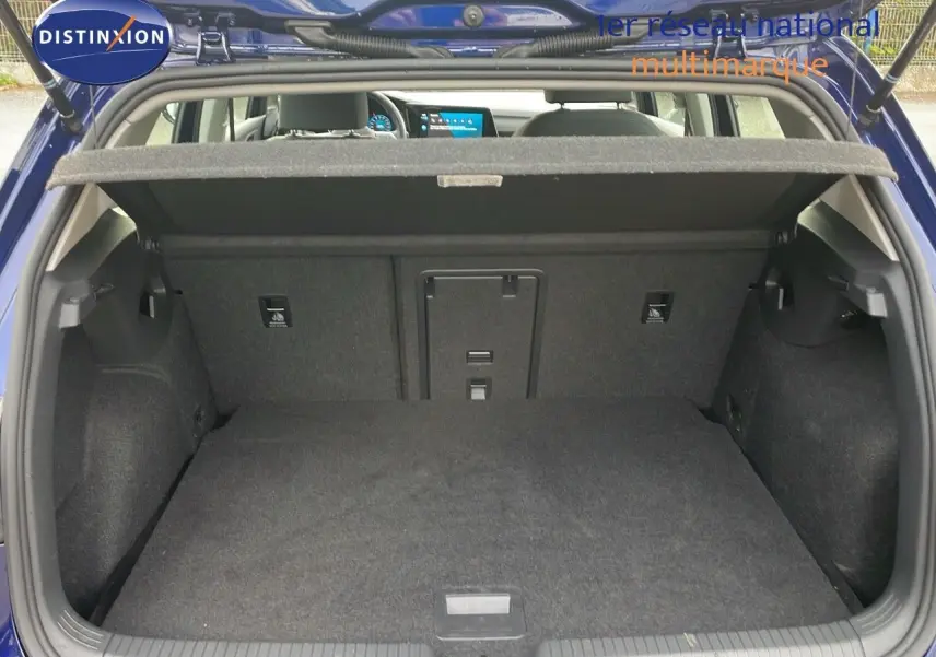 Coffre ouvert d'une Volkswagen Golf VIII bleu lapiz metal, vue arrière montrant l'espace de chargement vide et la tablette cache-bagages.