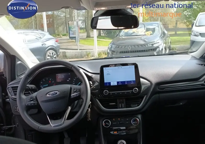Vue intérieure frontale du tableau de bord et volant noir du Ford Puma gris foncé 2023 avec écran tactile central et boîte manuelle.