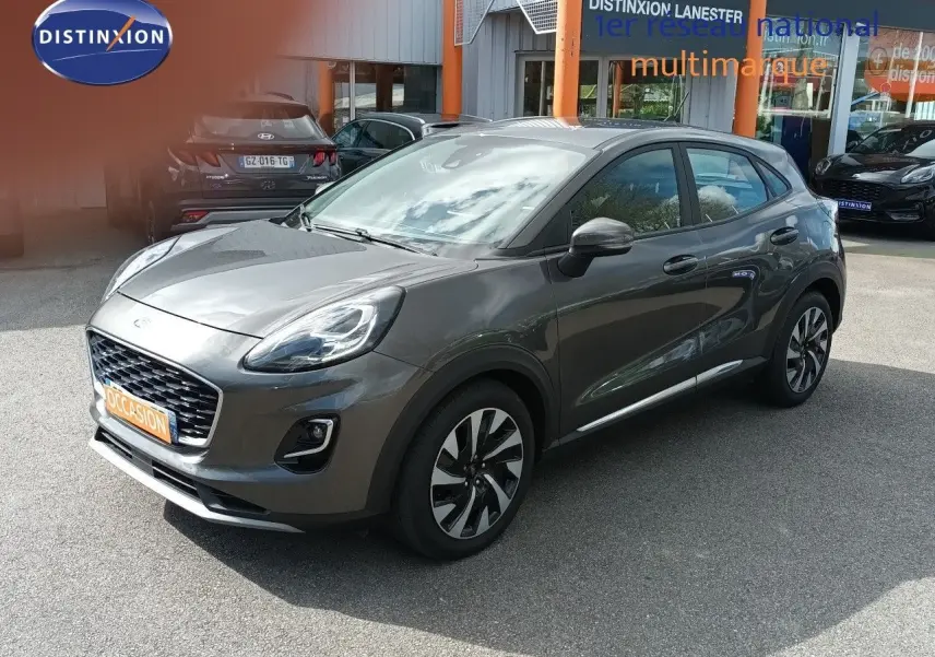 Ford Puma gris foncé métal en vue 3/4 avant droit, avec jantes alliage et calandre distinctive Titanium.