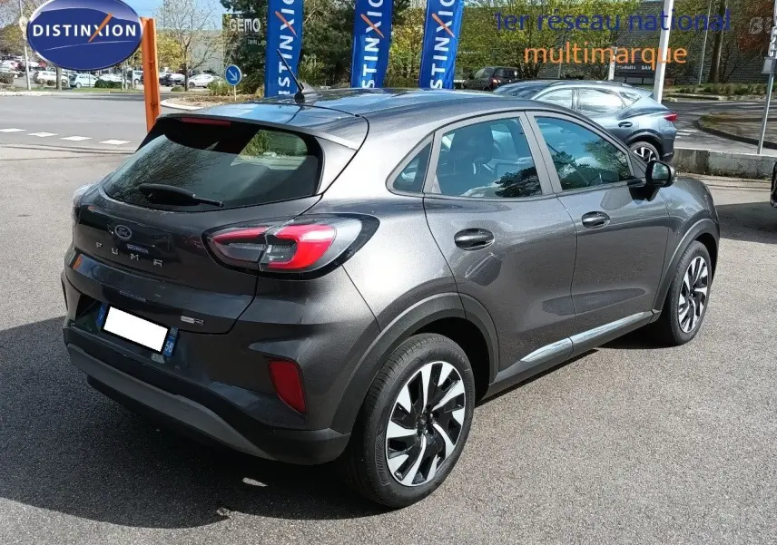 Vue 3/4 arrière droite d'un Ford Puma gris foncé métal 2023 avec jantes alliage et feux arrière LED distinctifs.