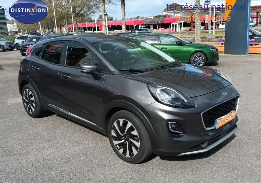Ford Puma gris foncé métal vue 3/4 avant droit, avec calandre noire et jantes bicolores distinctives.