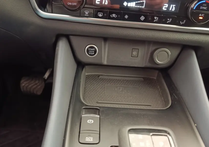 Vue rapprochée de la console centrale noire du Nissan Qashqai 2023, avec bouton start/stop et commande frein électrique.