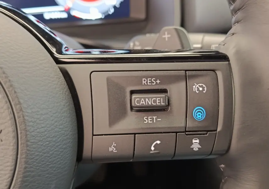Gros plan sur les commandes de régulateur de vitesse au volant cuir noir du Nissan Qashqai 1.3 MHEV Tekna 2023.