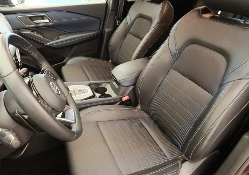 Vue intérieure côté conducteur du Nissan Qashqai 2023, sièges en cuir noir et volant multifonctions.