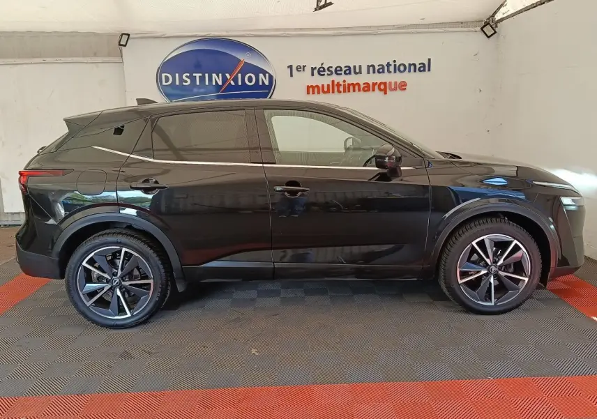 Profil côté gauche du Nissan Qashqai noir 2023, avec jantes alliage et vitres teintées, en intérieur showroom.